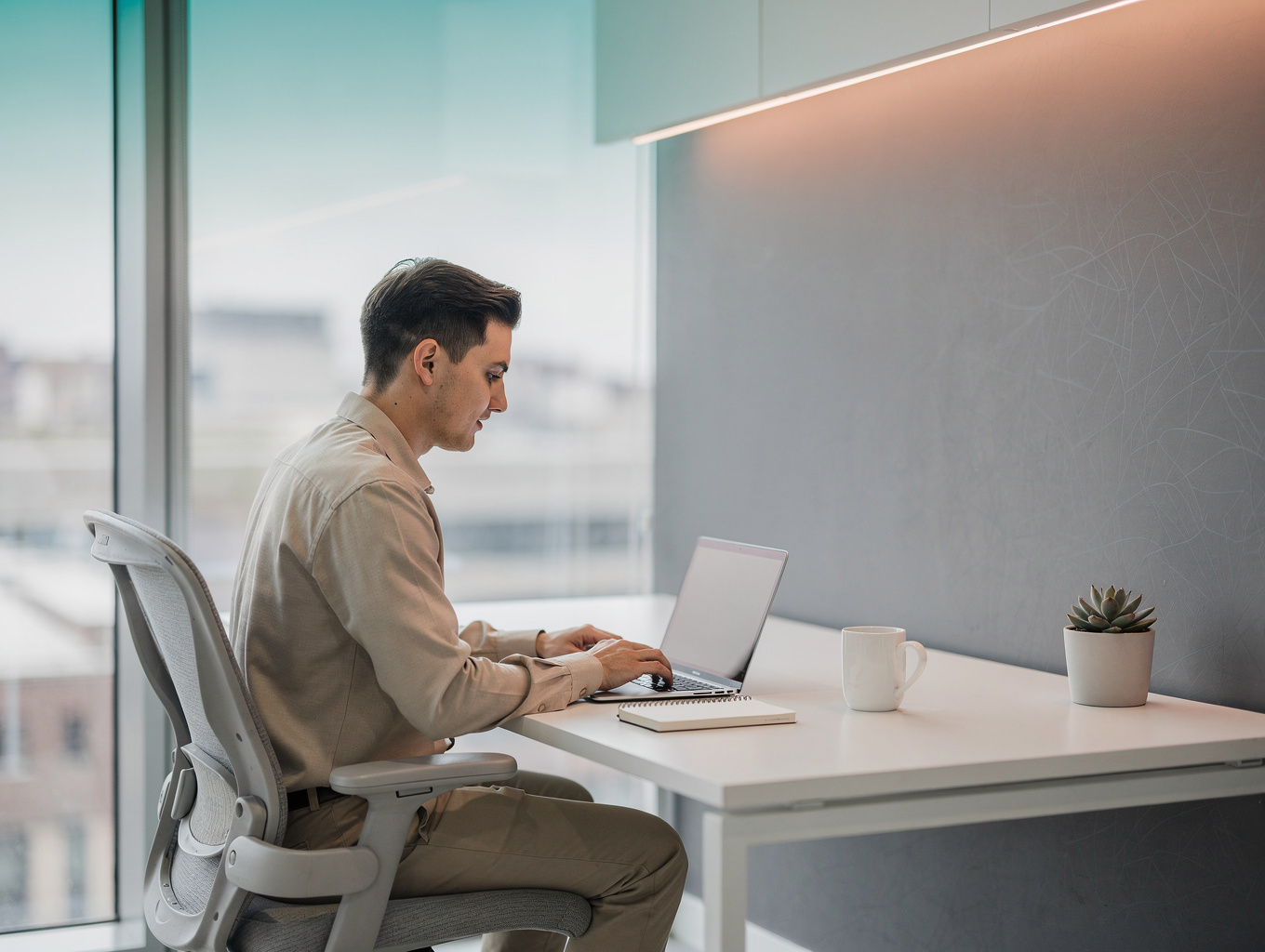Person working on a laptop at a bright home desk setup