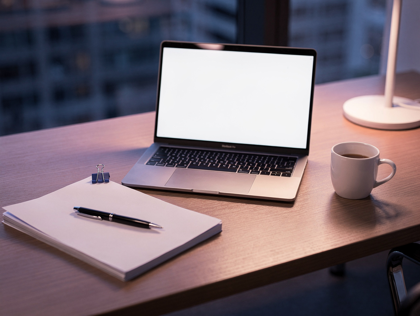 Desk lamp illuminating a tidy workspace during an evening working session